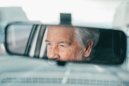 PensioenChauffeur kijkt in de achteruitkijkspiegel